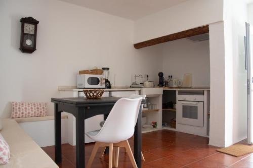 eine Küche mit einem Tisch und 2 weißen Stühlen in der Unterkunft Casa dos Marianinhos in Elvas