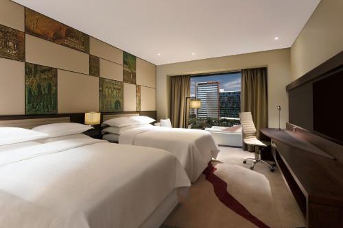 a hotel room with three beds and a flat screen tv at Sheraton Grand Bengaluru Whitefield Hotel & Convention Center in Bangalore