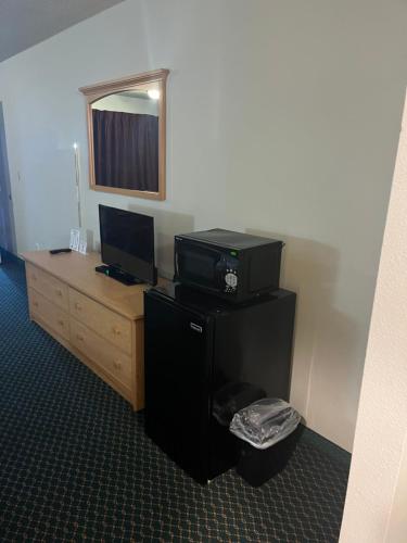 a room with a desk with a computer and a television at Western Inn Lakewood in Lakewood