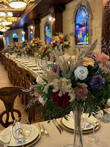 a long table with plates and vases filled with flowers at Dinasty Hotel in Tirana