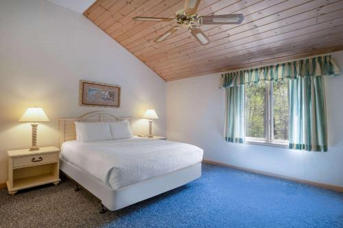 una camera con letto e ventilatore a soffitto di Southcape Resort Mashpee a Ramada by Wyndham a Mashpee