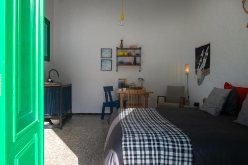 a bedroom with a bed and a table and a green door at Hektor - farm, arts & suites in Teguise
