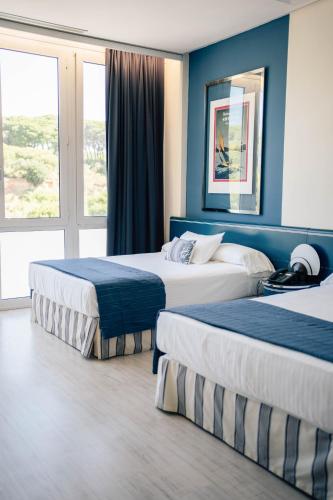 two beds in a hotel room with blue walls at Hotel Puerto Sherry in El Puerto de Santa María