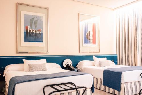 two beds in a room with blue and white walls at Hotel Puerto Sherry in El Puerto de Santa María