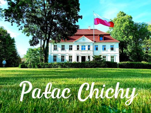 a flag flying in front of a white house at Pałac Chichy in Małomice