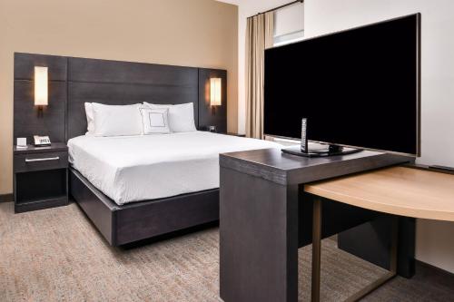 a bedroom with a bed and a desk with a television at Residence Inn by Marriott Charlotte Northlake in Charlotte