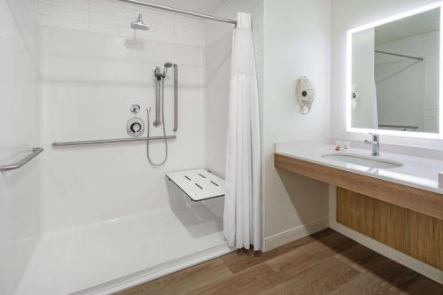 a white bathroom with a shower and a sink at Microtel Inn & Suites by Wyndham Summerside in Summerside