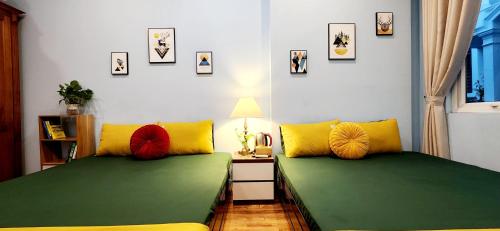 two beds with green and yellow pillows in a room at Hanoi Cozy Homestay Long Biên in Hanoi