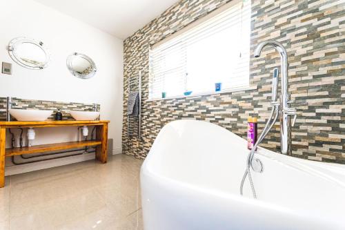 a bathroom with a tub and two sinks at Luxury 4 Bed, 3 Bathroom, Pet Friendly Villa, Sleeps 8, with Hot Tub in Trearddur Bay in Trearddur