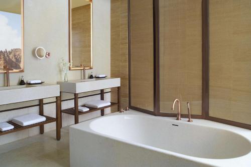 a bathroom with two sinks and a bath tub at Banyan Tree AlUla in Al-ʿUla