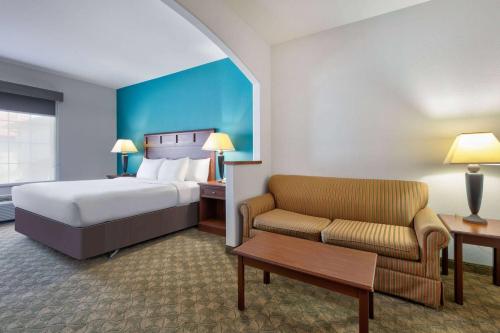 a hotel room with a bed and a couch at Baymont Inn & Suites by Wyndham Glen Rose in Glen Rose