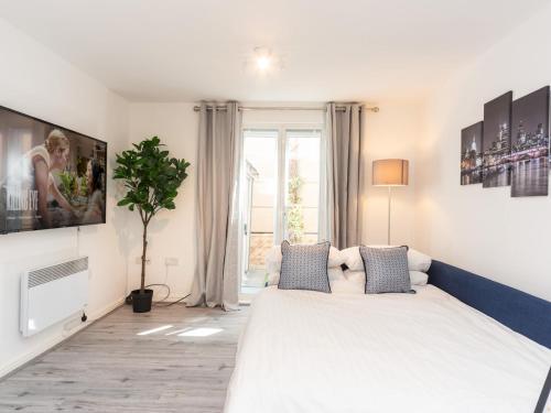 um quarto com uma grande cama branca e uma televisão em Pass the Keys Fresh and Stylish Central Flat With Parking and Garden em Londres