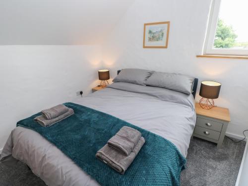 um quarto com uma cama com duas toalhas em The Loft Wisteria Cottage em Saundersfoot