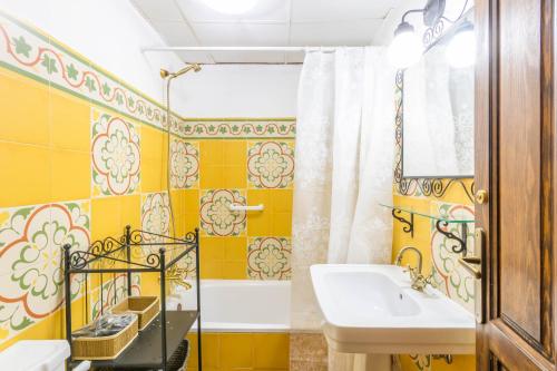 uma casa de banho amarela com um lavatório e um chuveiro em Macarena Muralla Encantada em Sevilha