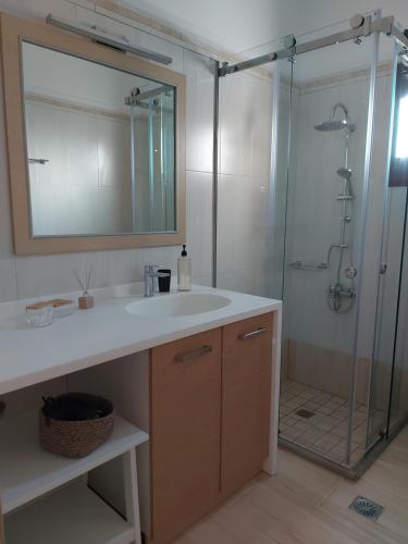 a bathroom with a sink and a shower with a mirror at Sea breeze houses in Monolithos