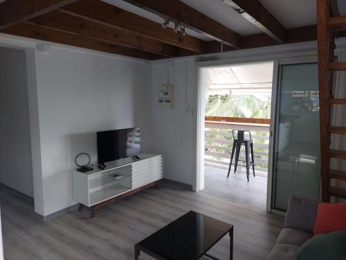 a living room with a couch and a television at T3 2 chambres plus mezzanine Saint leu 3mn à pied du lagon in Saint-Leu