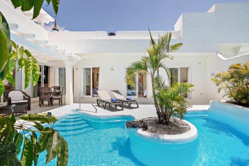 a pool with a palm tree in a house at Privè Royal Villa Bahiazul in Corralejo