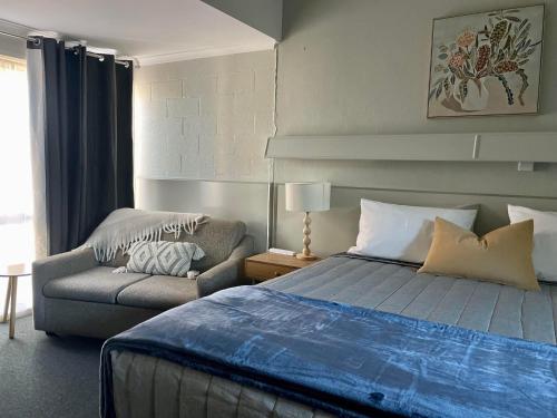 um quarto com uma cama, uma cadeira e um sofá em Tarra Motel em Yarram