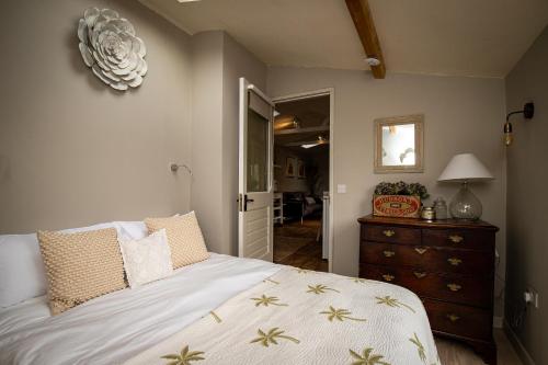 a bedroom with a bed and a dresser and a mirror at Treetops Lodge, Bantham, South Devon, a tranquil rural retreat in Aveton Gifford