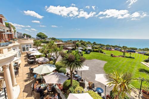 an outdoor patio with tables and umbrellas and the ocean at Hotel Miramar in Bournemouth