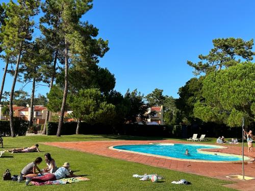 a group of people laying in the grass near a swimming pool at Forest Terrace Praia de Mira in Praia de Mira