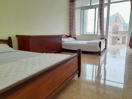 een slaapkamer met 2 bedden en een groot raam bij Nhà khách Sở Giáo Dục in Tam Ðảo