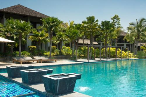 a swimming pool at a resort with palm trees at Pattara Resort & Spa in Phitsanulok