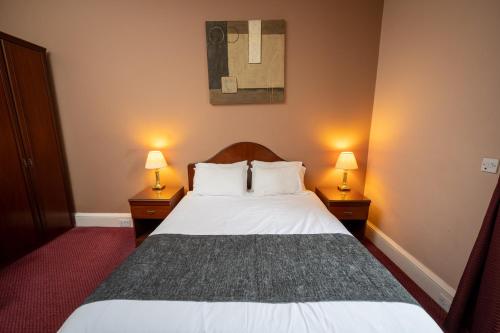 a bedroom with a white bed with two lamps at Edinburgh Whisky House Hotel in Edinburgh