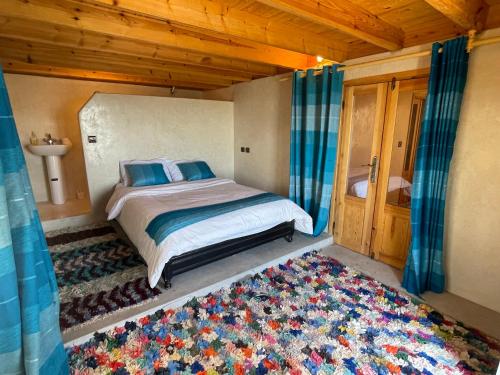 una camera da letto con un letto con cuscini blu e un tappeto di Dar Nouha : un appartement sur l'océan a Wassane