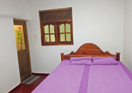 a bedroom with a bed with purple sheets and a window at Deer Garden Guest in Polonnaruwa