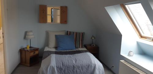 Dormitorio pequeño con cama con almohada azul en le jardin de lumiere en Pontchâteau