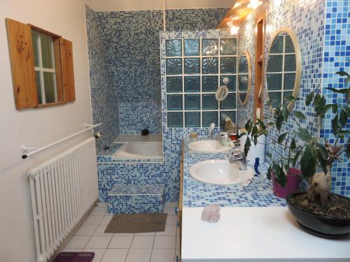 a blue tiled bathroom with two sinks and a tub at le jardin de lumiere in Pontchâteau