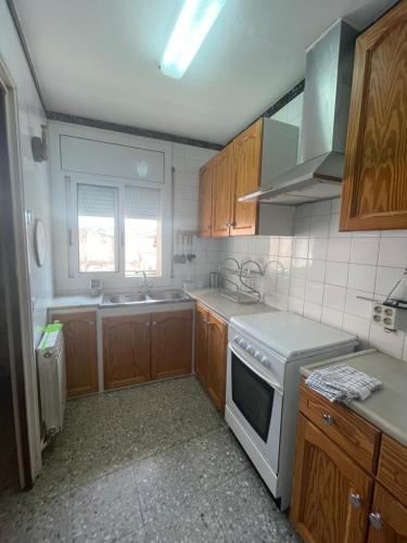 a kitchen with wooden cabinets and a white stove top oven at Mas del Llorenç in Ulldemolins
