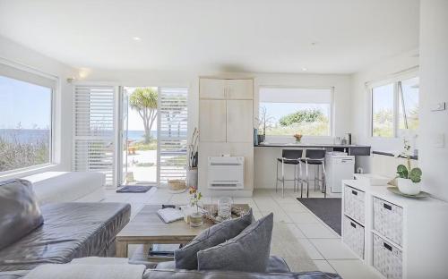 a white living room with a couch and a kitchen at Saltwater - Absolute Oceanfront, Fire Pits, some Villas with Hot Tubs and Sauna in Falmouth