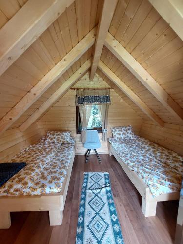 Zimmer im Dachgeschoss mit 2 Betten und einem blauen Stuhl in der Unterkunft Căbănuță la Munte cu Piscină in Bistra