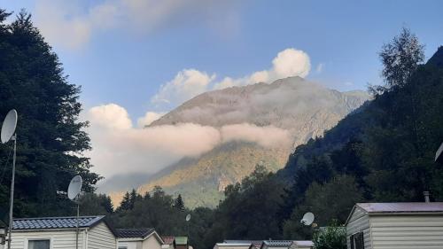 uma montanha obscurecida por nuvens com casas e árvores em LOGEMENT AU COEUR DE PYRENEES em Aragnouet