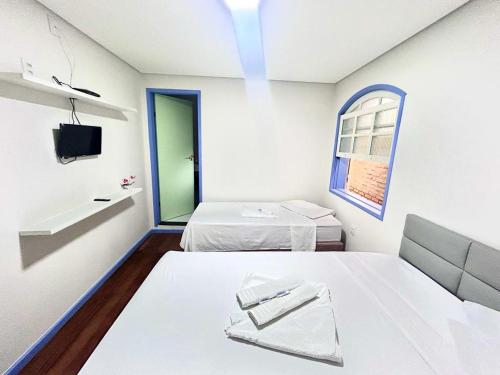 Cette chambre blanche dispose de deux lits et d'une fenêtre. dans l'établissement Ouro Preto Suítes, à Ouro Preto