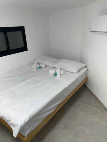 een bed met witte lakens en kussens in een kamer bij dahan's 770 - דהן 770 in Safed