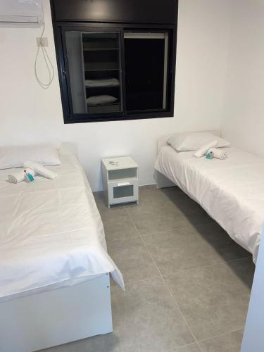 two beds in a room with a window and a table at dahan's 770 - דהן 770 in Safed