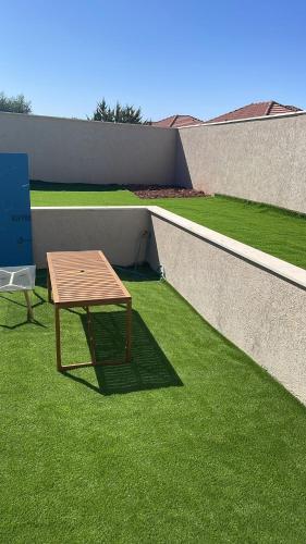 a wooden table on the grass next to a wall at dahan's 770 - דהן 770 in Safed