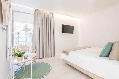 a white bedroom with a bed and a table at LODO Suits Ria - Private Room by HD in Faro