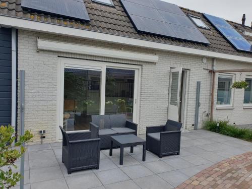 a patio with two chairs and a table with solar panels at Aangepast vakantiehuis Sandra mindervaliden in Limmen
