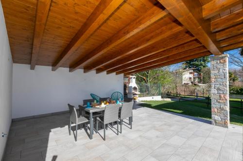 a patio with a table and chairs under a wooden ceiling at Villa Il Gelsomino Bellavista - Happy Rentals in Besozzo