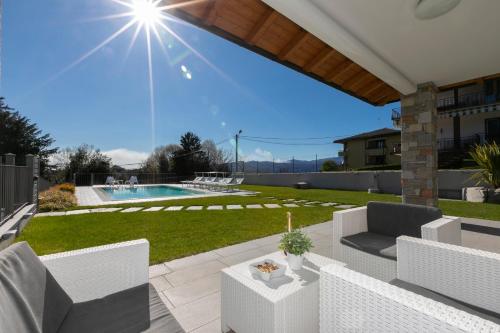 a patio with white chairs and a pool at Villa Il Gelsomino Bellavista - Happy Rentals in Besozzo