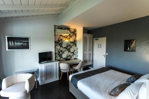 a bedroom with a bed and a desk with a television at HOTEL restaurant CÔTE GARONNE le BALCON DES DAMES - Tonneins Marmande Agen - chambres climatisées in Tonneins