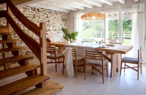 ein Esszimmer mit einem Tisch, Stühlen und einer Steinmauer in der Unterkunft Wishome-Casa con piscina climatizada, cerca Comillas in Valdaliga 