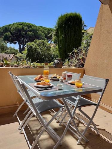 une table avec des assiettes de nourriture et des verres de jus d'orange dans l'établissement Le P'tit Cocon: chambre / terrasse / parking, à Cavalaire-sur-Mer