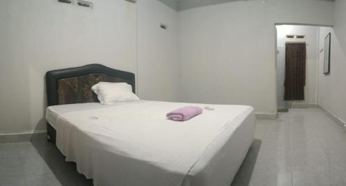 a white bed with a purple pillow on top of it at Pika Homestay in Plambi