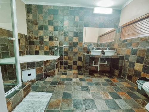 a bathroom with two sinks and two mirrors at Four Seasons Guesthouse - Hardekool 7 in Lephalale