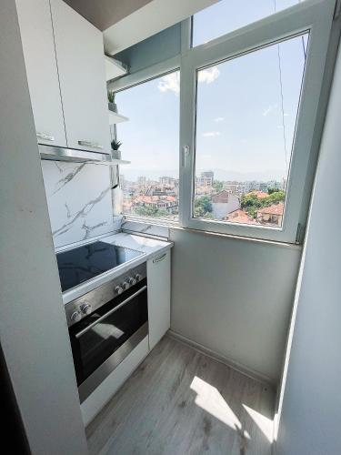 a kitchen with a stove and a large window at Amazing view central 1 bedroom apartment in Pazardzhik